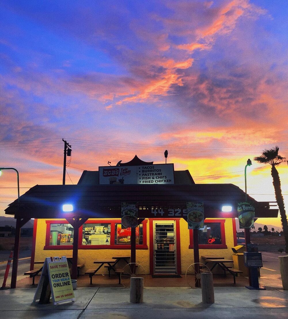 Their storefront at sunset: the red roof, the lit yellow walls and the pole sign